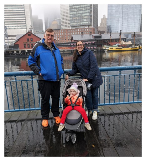 Ray poses with family members on a rainy day in front of a metropolitan riverfront