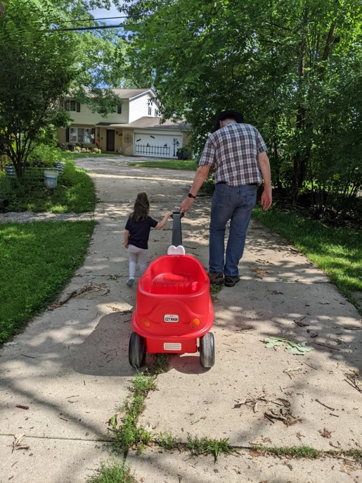 Ray Zick and his daughter pull a red wagon down a sunny driveway